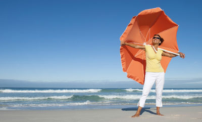 Frau mit Sonnenschirm am Strand
